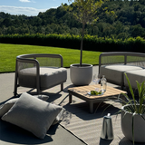 Utomhusmiljö med ett elegant soffbord i teak och pulverlackerad aluminium omgivet av loungestolar på en solig terrass från sackit