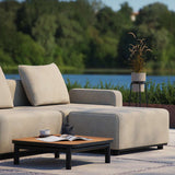 Beige modulär loungesoffa från sackit på terrass vid pool med soffbord och dekorativ kruka i en grön nordisk trädgård