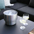 Rostfri vinkylare med is bredvid två glas med citrusdrinkar på ett svart soffbord i en nordisk loungemiljö från sackit