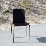 Svart utomhusstol från sackit med ergonomisk formgjuten sits och slanka metallben på en solbelyst uteplats vid sanddynerna