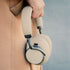 Beigea Touch 400 over ear hörlurar från sackit hålls i handen mot en neutral bakgrund med vadderade öronkåpor och modern design