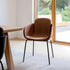 Brun läderstol med omslutande form och svarta metallben vid ett matbord i ett ljust nordiskt hem från sackit