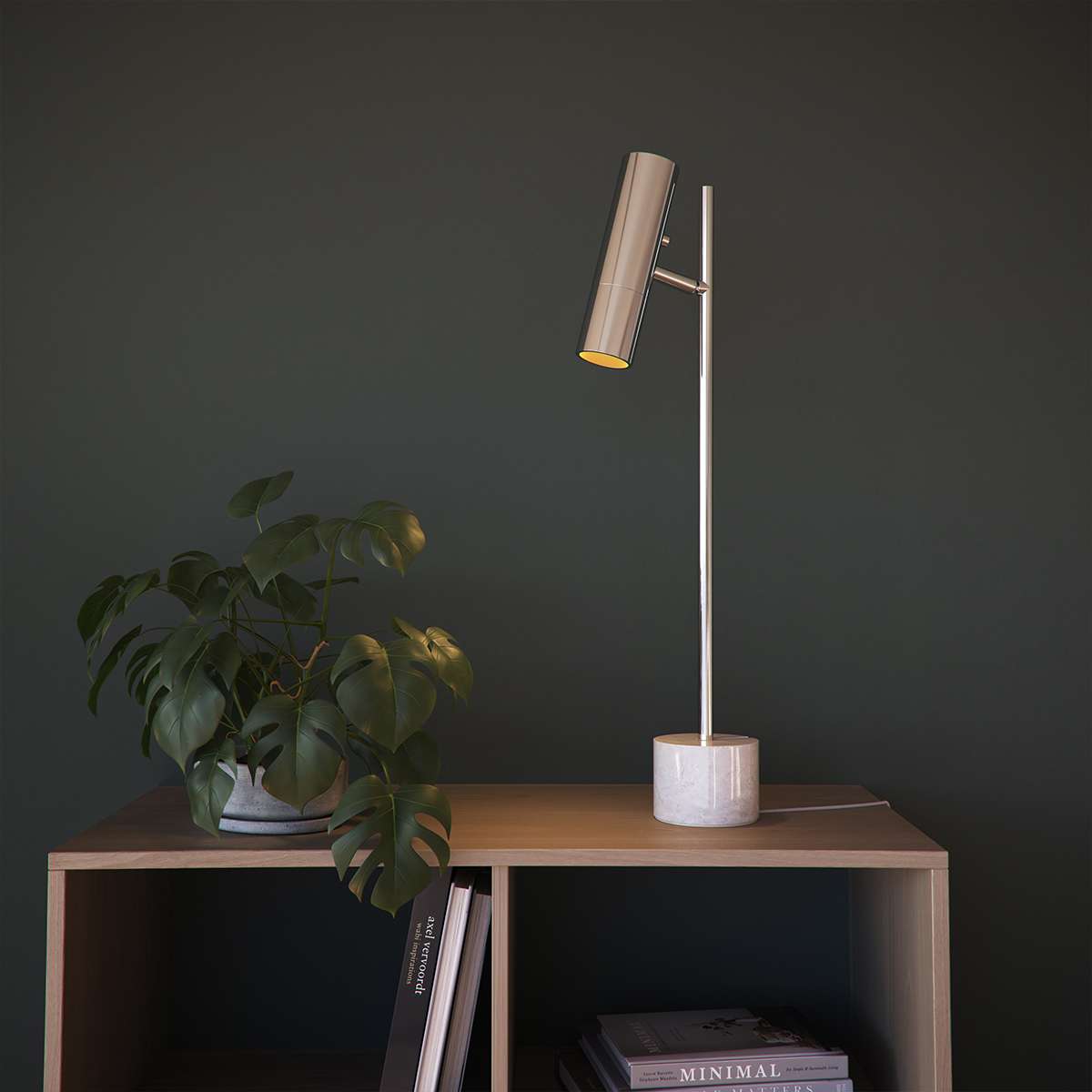 Elegant bordslampa från sackit med slank metallarm cylindrisk skärm och marmorfot på träskåp med växt i nordisk interiör