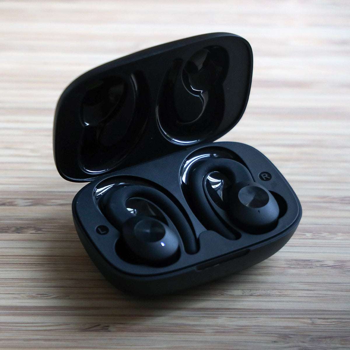 Black Active 200 wireless sports headphones with charging case and silicone ear tips and hooks on a white background