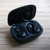 Black Active 200 wireless sports headphones with charging case and silicone ear tips and hooks on a white background
