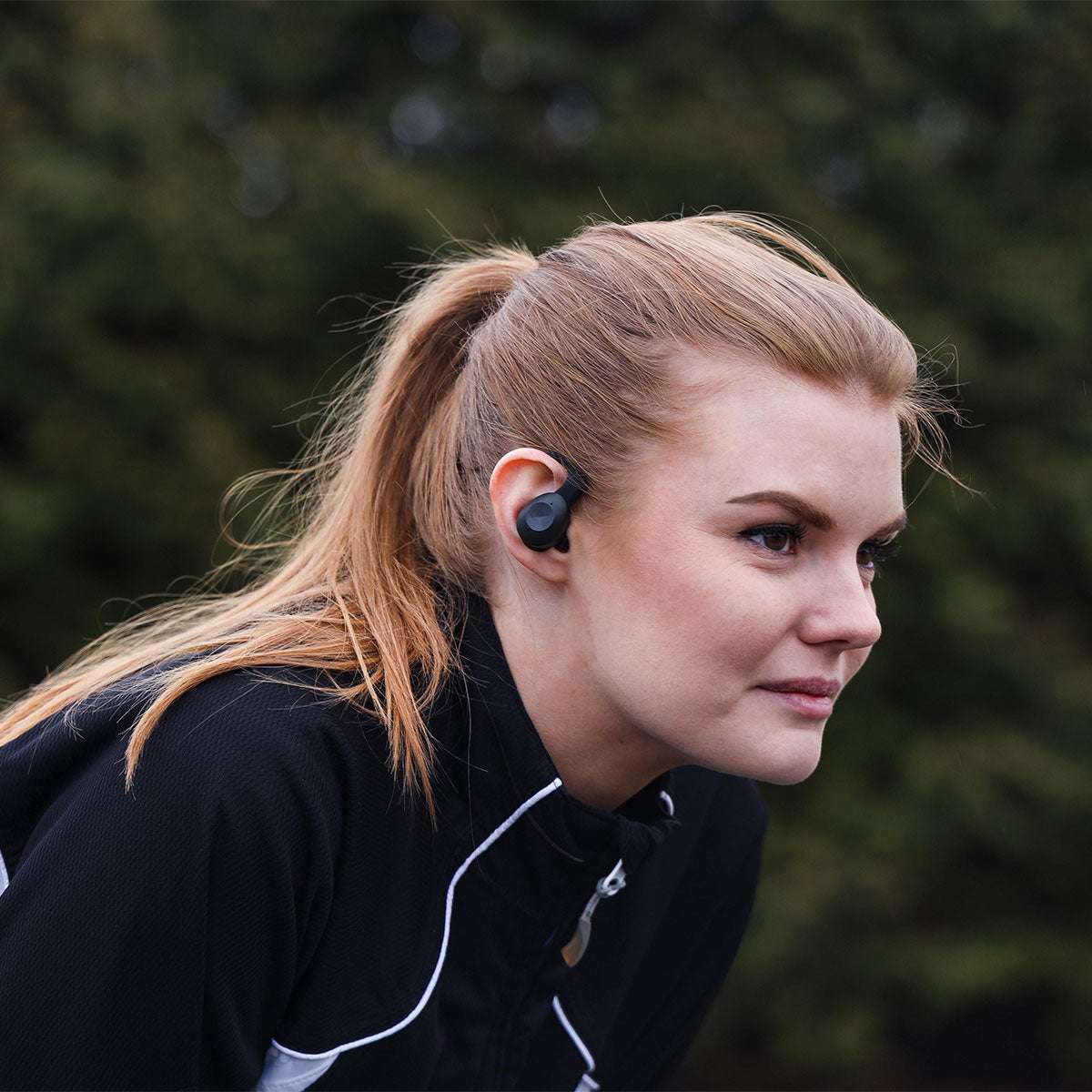Black Active 200 wireless sports headphones with charging case and silicone ear tips on white background.