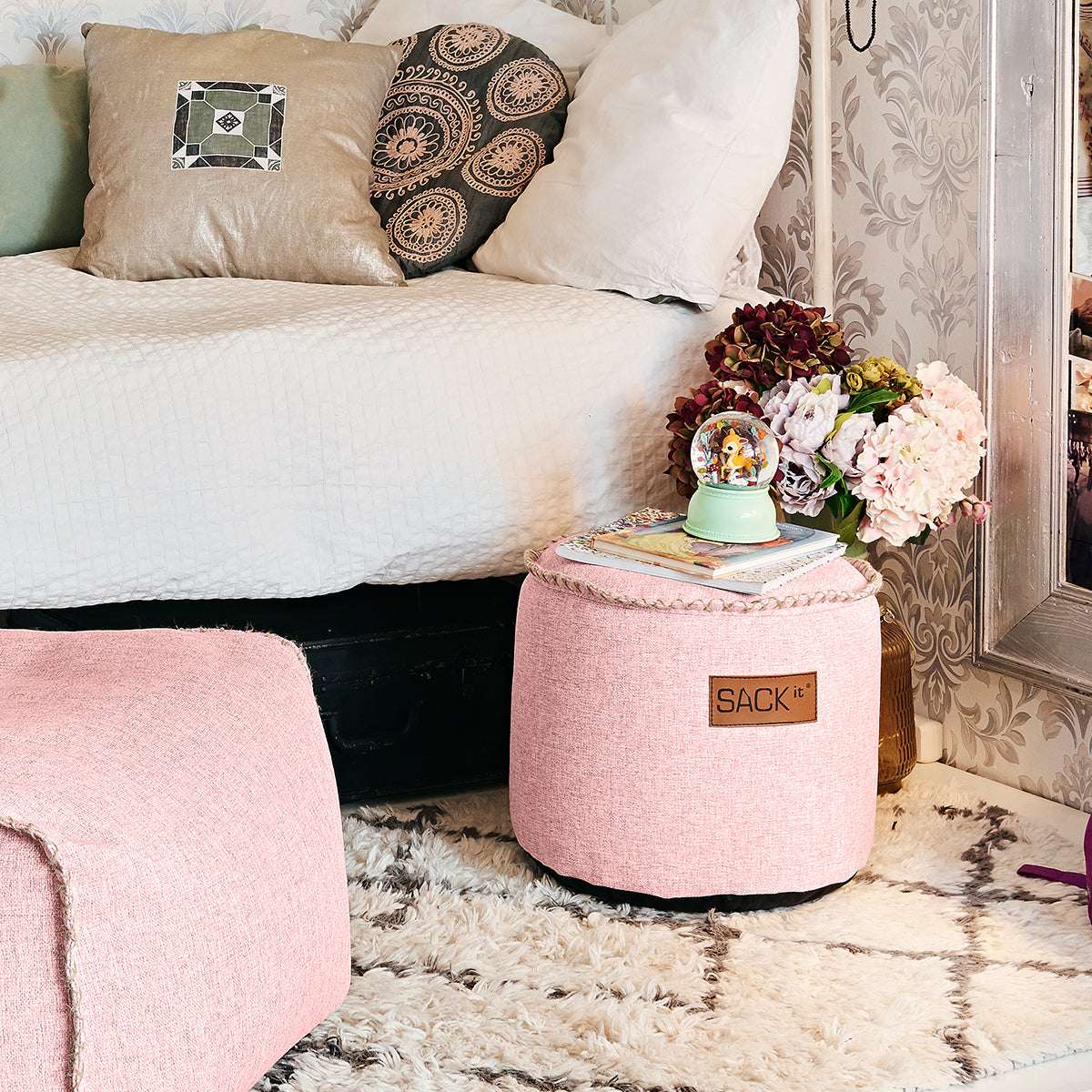 Rosa rund Cobana juniorpuff från sackit som extra sittplats i ett elegant sovrum med blommor kuddar och mjuk matta