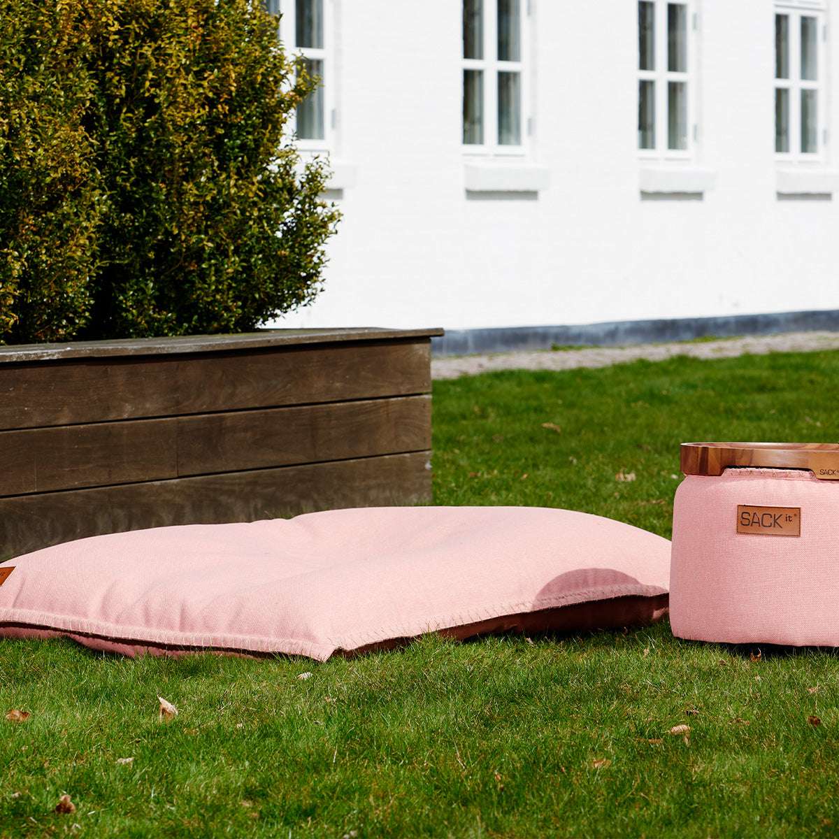 Rosa sackit Cobana sittsäck och matchande pall på gräsmatta utomhus framför ett vitt hus och en träplanteringslåda