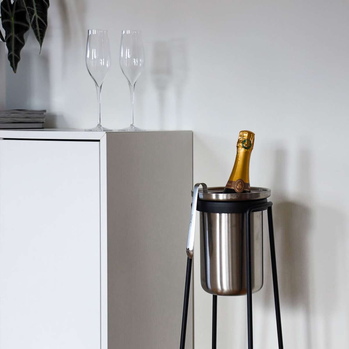 sackit vinkylare i rostfritt stål på svart stativ med champagneflaska i elegant nordisk inomhusmiljö