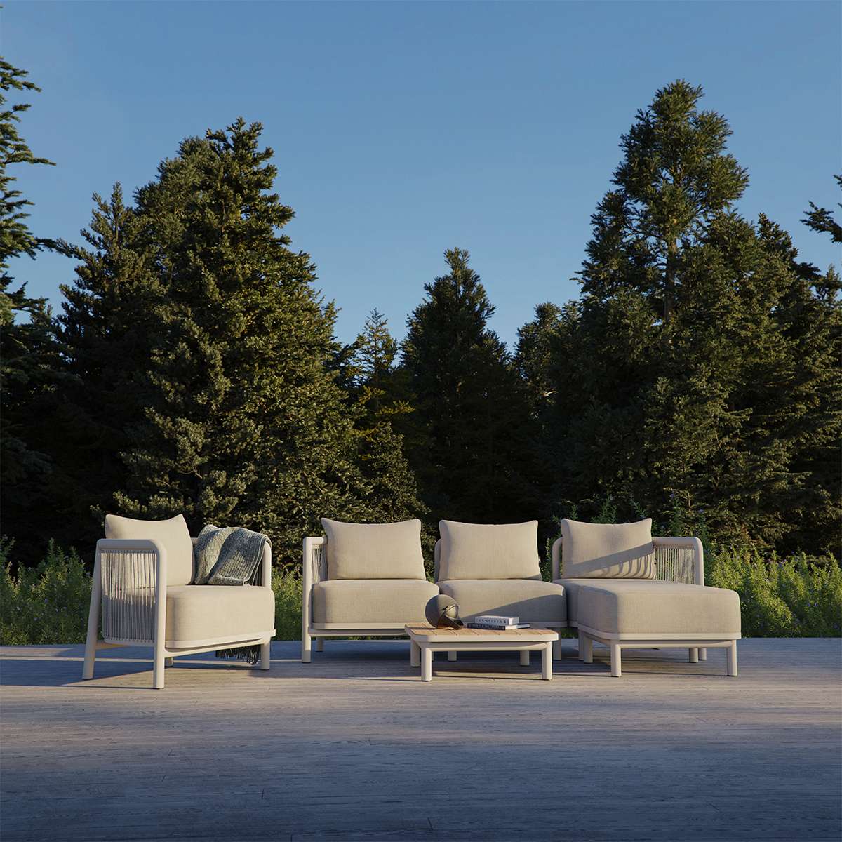Beige Kirra loungesoffa och fåtöljer från sackit Sweden med soffbord på en terrass omgiven av grönska och höga träd i nordiskt utomhuslandskap