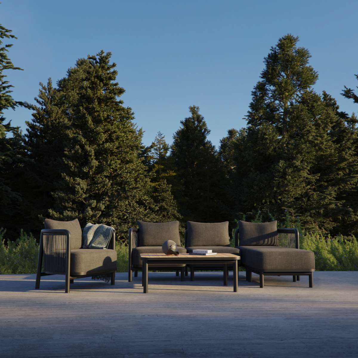 sackit Kirra loungesoffa i mörk textil med matchande fåtöljer och soffbord på en terrass omgiven av grönska för nordiskt utomhusliv