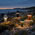 Fyra sladdlösa bordslampor från sackit lyser på klippor vid havet i skymningen med mjukt ljus och vädertålig design för nordiskt utomhusbruk